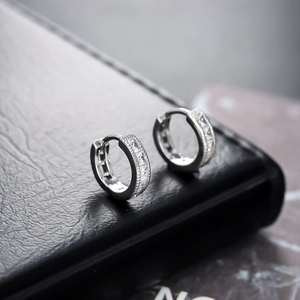 Pendientes de aro plateados con circonitas blancas brillantes sobre cuero negro