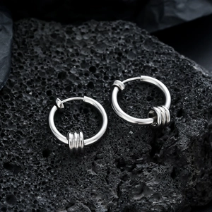 Silver circle clip earrings with three moving rings on black volcanic stone