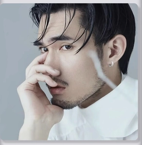 Close-up of a silver pavé hoop earring worn by a male model in white shirt