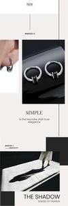 Détail macro de boucles d'oreilles cylindriques argent et noir en acier inoxydable poli
