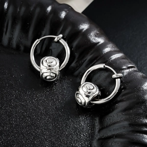 Boucles d'oreilles créoles argentées avec charm cylindre en spirale sur fond noir mat