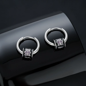 Polished silver titanium hoop earrings with sliding purple bear charm on black mirror