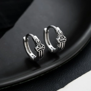 Retro titanium steel cross sword hoop earrings with vintage finish on black leather surface