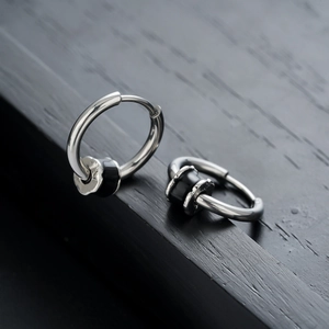 Boucles d'oreilles créoles en acier poli avec détail cylindre noir sur bois sombre
