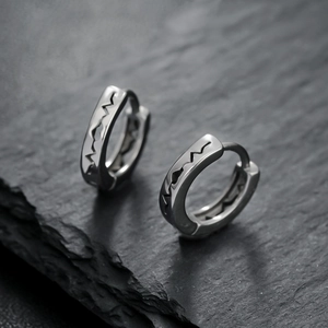 Polished titanium steel heartbeat earrings in silver on a textured stone background