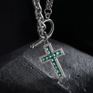 Collier croix en acier titane avec zircon vert et fermoir OT sur roche sombre
