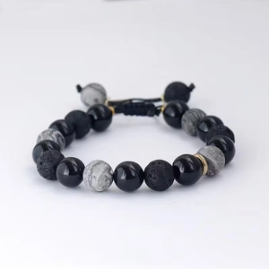 Detailed close-up of obsidian and lava stone beads with adjustable woven cord