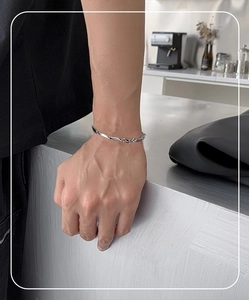 Bracciale a catena ritorta in argento da uomo indossato in un ambiente di caffè moderno