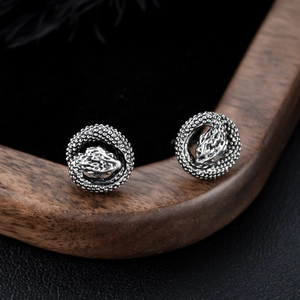 Vintage silver dragon head stud earrings with detailed engraving on dark wood background