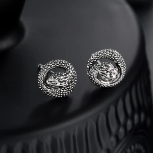 Silver snake hoop earrings with detailed scales and vintage design on black pedestal