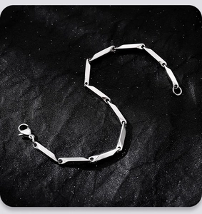 Bracciale a catena geometrica in argento lucido con chiusura a moschettone su fondo scuro