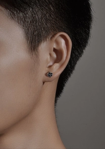 Vue latérale d'une boucle d'oreille étoile à quatre branches pour homme avec gemme noire