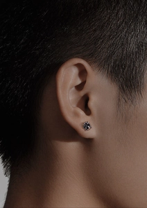 Détail d'un clou d'oreille pour homme avec pierre noire et monture argentée à quatre griffes