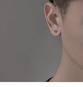 Gros plan sur un clou d'oreille trèfle minimaliste pour hommes au fini argenté poli