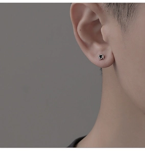 Détail macro d'un clou d'oreille carré noir sur oreille d'homme avec base en métal argenté