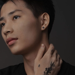 Boucles d'oreilles trèfle argentées pour hommes avec incrustation noire sur modèle