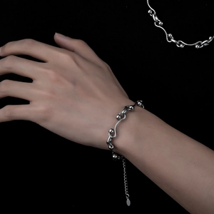 Minimalist silver interlocking wave bracelet with polished beads on a model wrist