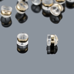 Silicone and gold metal S925 silver earring backs set on dark reflective surface