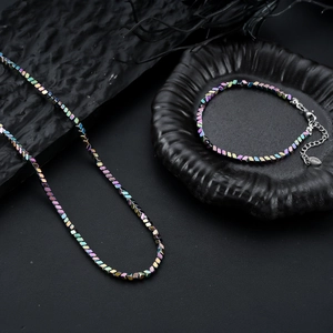 Regenboog roestvrijstalen kubusvormige kralen ketting en armband set op rots