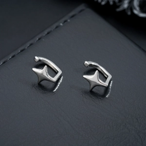Minimalist silver four-pointed star ear cuffs in high-gloss metal on black leather