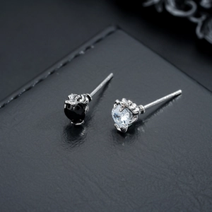 Modern zircon stud earrings set in silver claw setting on dark leather background