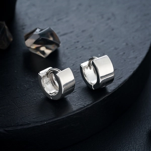 Boucles d'oreilles huggie carrées en argent poli pour hommes et femmes sur socle noir