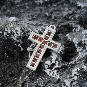 Vue macro d'un pendentif croix en argent avec grenats rouges et pavé de pierres blanches