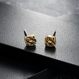 Vintage golden square stud earrings with relief pattern on black display stand