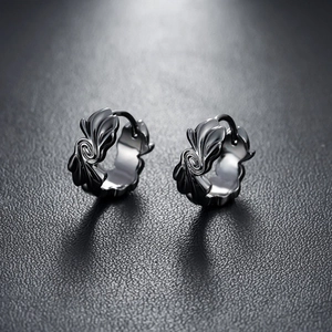 Macro-opname van gunmetal oorringen met gotisch vleugelpatroon op zwart leer