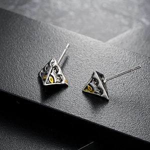 Boucles d'oreilles triangle argentées avec motif œil sur support de présentation noir