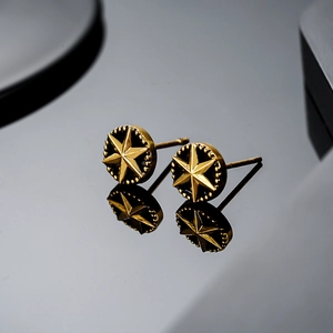 Boucles d'oreilles hexagrammes dorées avec émail noir et texture perlée sur fond
