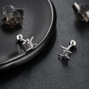 Punk style silver knot stud earrings with barbed wire design on black leather texture