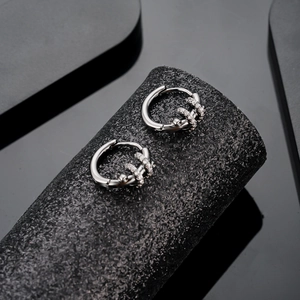 Silver snake-inspired hoop earrings with micro-inlaid cubic zirconia on a black stand