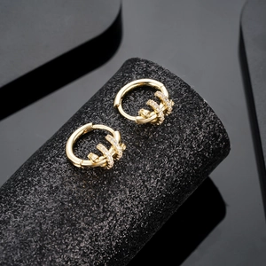 Luxury gold hoop earrings with white zircon geometric design on a black display stand
