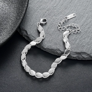 Polished stainless steel leaf-link chain bracelet with lobster clasp on dark stone background