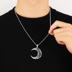 Silver crescent moon necklace with engraved rose pattern worn on black knitwear