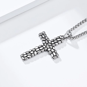 Macro detail of vintage cobblestone textured cross pendant with braided wheat chain