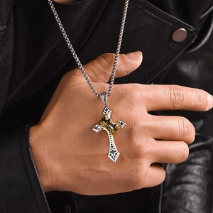 Détail d'un pendentif croix argenté vintage avec couronne dorée sur collier homme