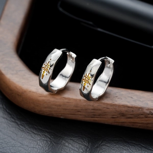 Retro hammered silver hoop earrings with gold sun engraving on dark leather surface