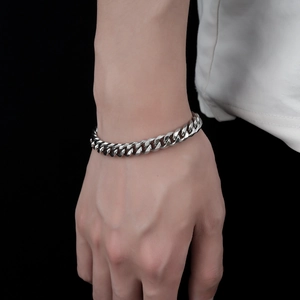 Close-up of polished stainless steel Cuban link bracelet worn on wrist with black background
