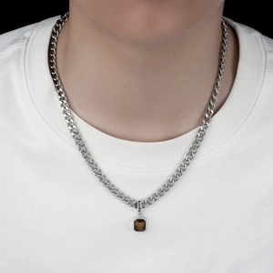 Macro detail of men's Cuban chain with a Lucky engraved tiger eye stone pendant