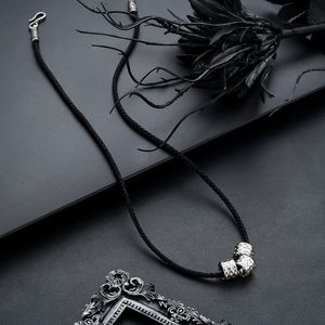 Detail of silver cylindrical beads on black braided cord with an S-hook clasp