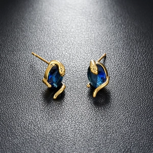 Détail de boucles d'oreilles serpent avec pierre bleue et plaqué or 18 carats