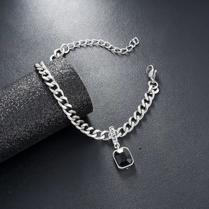 Detail of silver Cuban link bracelet featuring a black rectangle pendant and Lucky charm tag