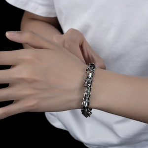 Close-up of vintage silver dragon bone chain bracelet worn on a man's wrist with industrial style