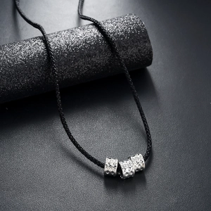Detail of silver cylindrical beads with hammered texture on black woven cord necklace