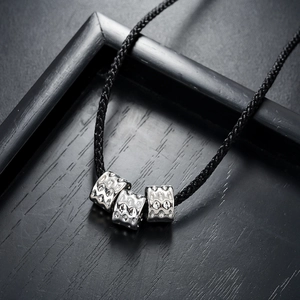 Detail of three textured silver square beads on a black woven cord necklace for men and women