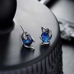 Détail macro du clou d'oreille serpent en argent avec incrustation de pierre bleue