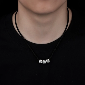 Detail of silver hammered cylinder pendants on a black woven necklace cord worn by model