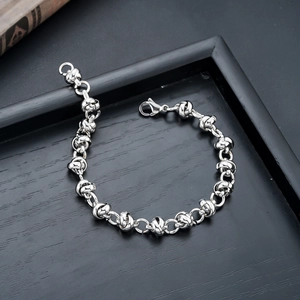 Silver stainless steel knot chain bracelet with lobster clasp on dark wood background